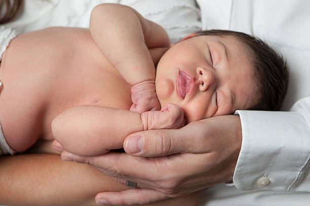istock Newborn Baby Sleeping in Parents Arms 498062423