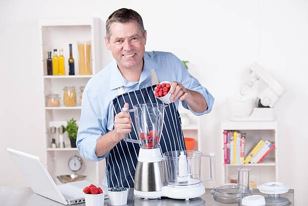 istock Mature Man Pouring Raspberries Into Blender While Making Smoothie/ Dessert 498062778