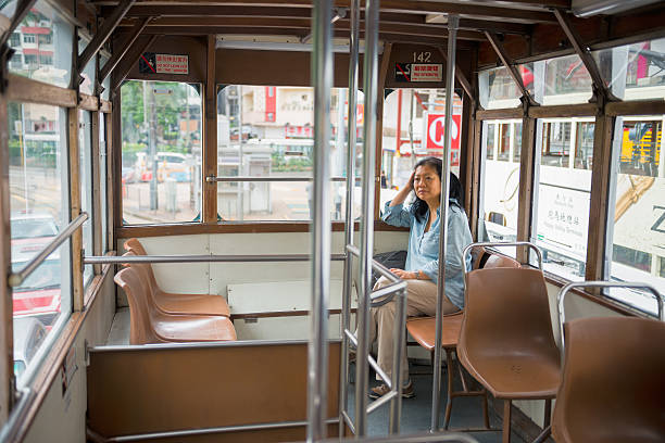 An Asian woman sits at the rear of the top deck of a Hong Kong tram.  Hong Kong Island.