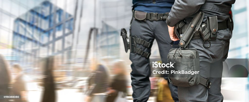 Armed policemen Armed policemen on guard in busy street with modern glass buildings and people walking Security Guard Stock Photo