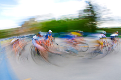 A group of female bicycle racers ride together in a pack during a criterium road race.