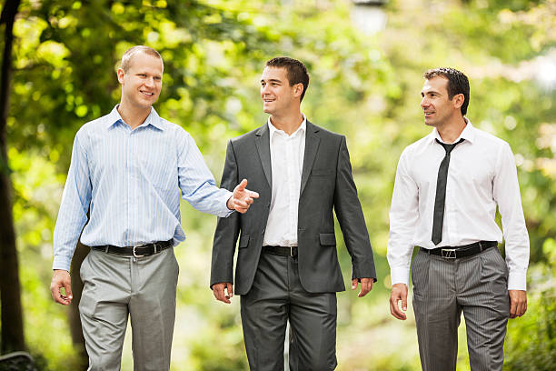 Three smiling businessmen walking in the park and communicating.   