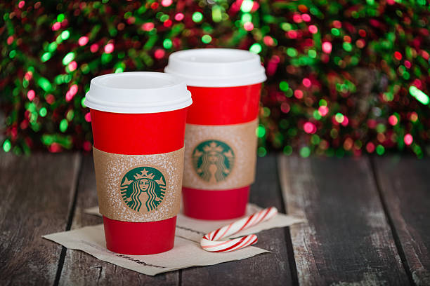 Starbucks holiday beverage Dallas, TX, USA - November 21, 2015: A cup of Starbucks popular holiday beverage, served in the new 2015 designed red holiday cup. Displayed against dark rustic table and sparkly holiday background. starbucks red cup stock pictures, royalty-free photos & images