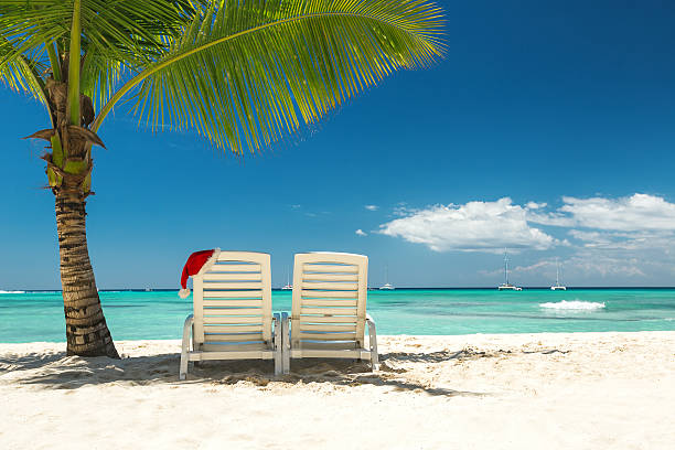 Santa's hat and sun loungers on the tropical beach Panorama of sun loungers with Santa hat at beautiful tropical beach with white sand and turquoise water, perfect Christmas vacation maldivian culture stock pictures, royalty-free photos & images