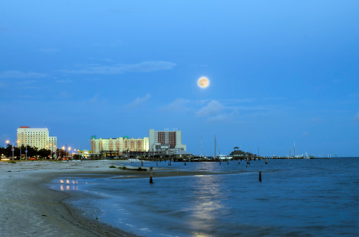 Biloxi, Mississippi, casinos and buildings along Gulf Coast shore in night time image with rising moon