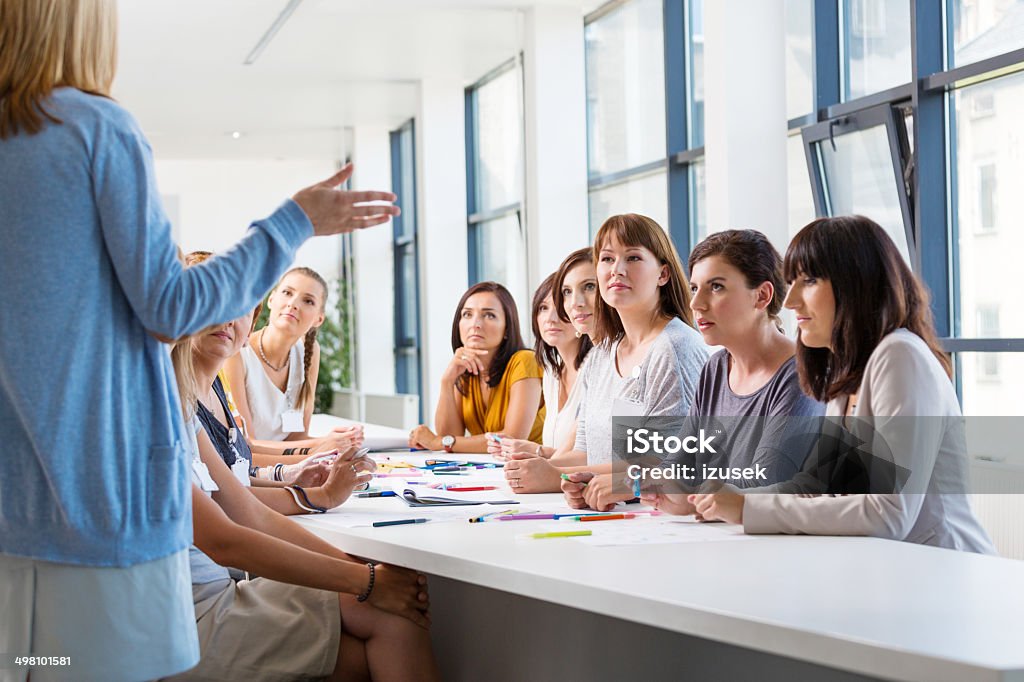Group of women at the training Group of women attending a training, listening to the female coach. Casual Clothing Stock Photo