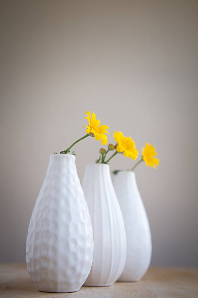 Tre vasi bianco con fiori gialli su tavolo in legno. - foto stock