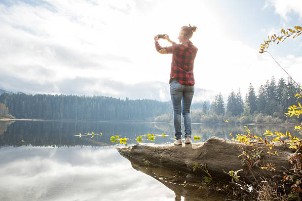 istock Woman standing on tree log photographing landscape 498112586