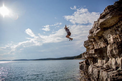 A group of friends jump from cliffs into the lake.