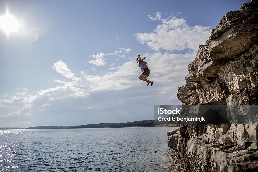 Cliff Jumping A group of friends jump from cliffs into the lake. Cliff Jumping Stock Photo