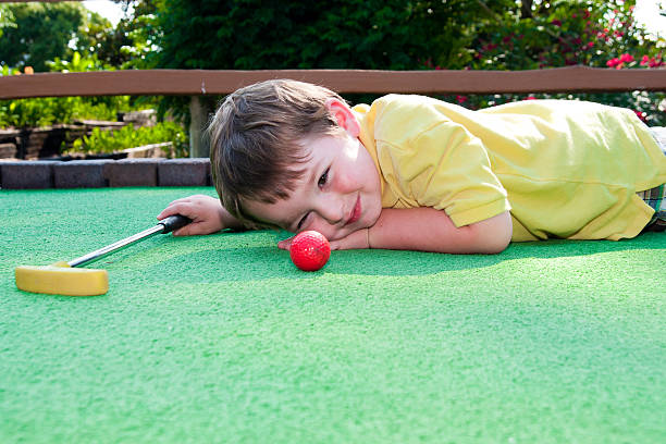 Young boy playing mini golf stock photo