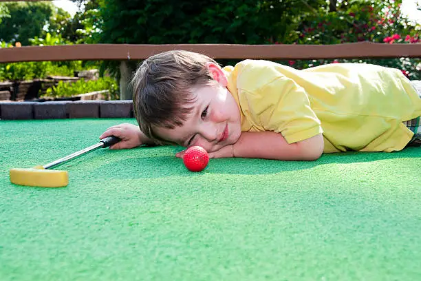 Young boy plays mini golf on putt putt course