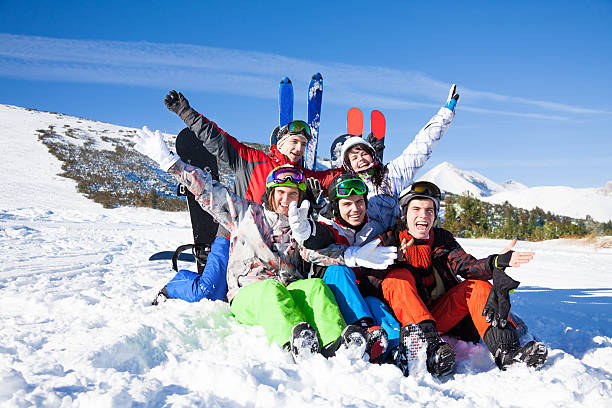 istock Sitting friends with snowboards lifting hands up 498115393