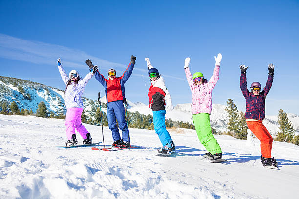istock Skier and snowboarders in a row lifting hands up 498115443