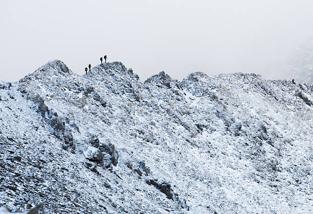 Striding Edge in Winter 4 Ice Climbers making their way across Striding Edge in the Lake District.  striding edge stock pictures, royalty-free photos & images