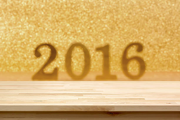 Wood table top on blur golden glittering 2016 background