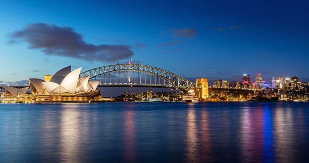 Sydney Skyline at Night Sydney skyline at twilight. Panorama of the Sydney Skyline. The Sydney Opera House small on the left side, Sydney Harbour Bridge in the middle. Twilight Scenic Sydney Panorama. Sydney, Australia. Canon 5DSR 50MPixel Panorama. sydney harbor photos stock pictures, royalty-free photos & images