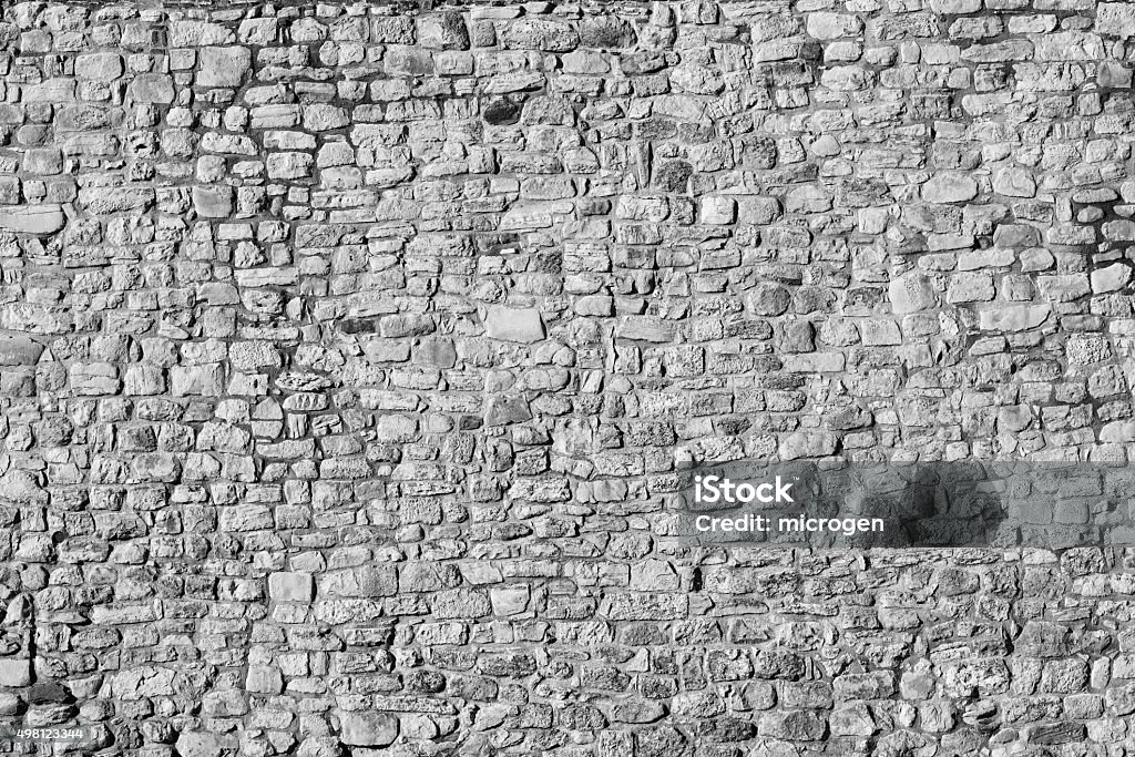 Old stone wall background, black and white Old authentic stone wall background in black and white Stone Wall Stock Photo