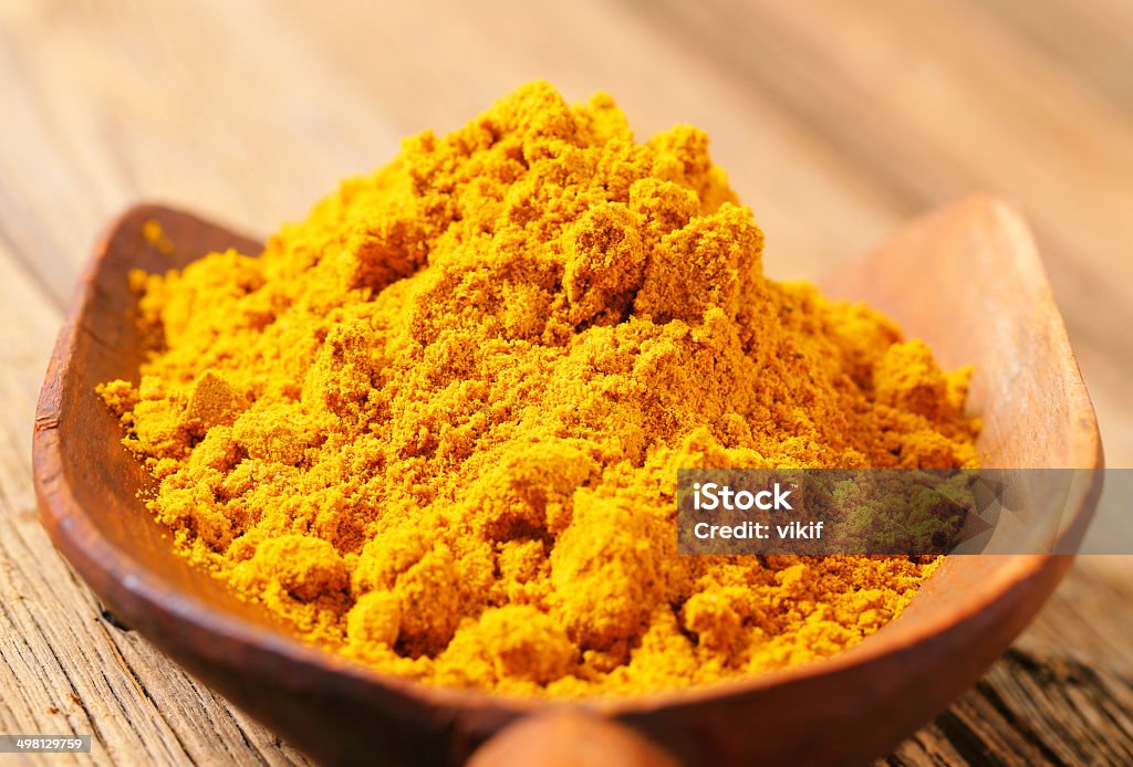 Curry powder Heap of curry powder on a wooden scoop Chilli Powder Stock Photo