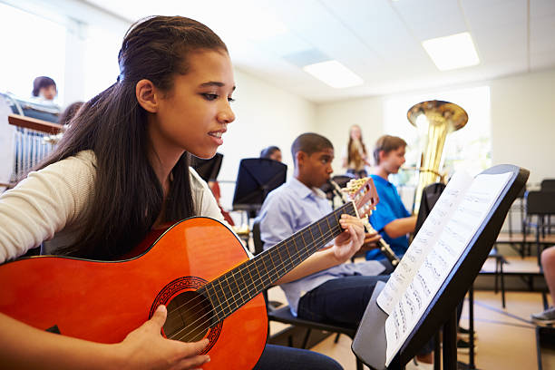 femmina pupilla suona chitarra in high school orchestra - guitar child music learning foto e immagini stock