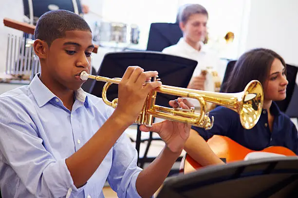 Photo of Male Pupil Playing Trumpet In High School Orchestra