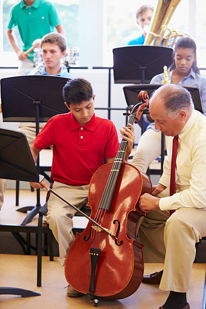 istock Boy Learning To Play Cello In High School Orchestra 498131135