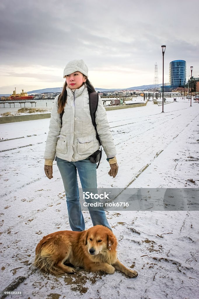 Woman stands with strayed dog In Punta Arenas, Chile Snow Stock Photo