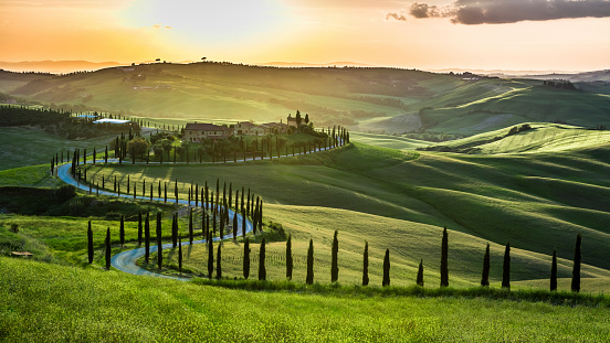 Sunset over the winding road with cypresses in Tuscany.