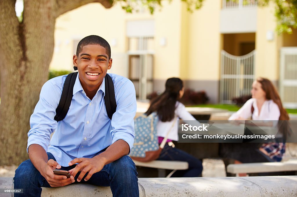 Male High School Student Using Phone On School Campus Male High School Student Using Phone On School Campus Smiling To Camera High School Student Stock Photo