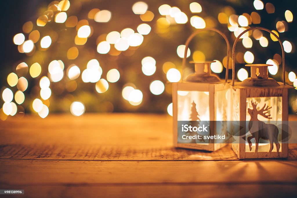Cozy Christmas holidays. Close-up of lanterns with candles on wooden background. Sparkling lights in background.  Evening or night scenes. Christmas Stock Photo