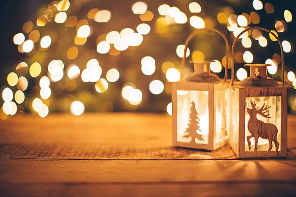 Close-up of lanterns with candles on wooden background. Sparkling lights in background.  Evening or night scenes.