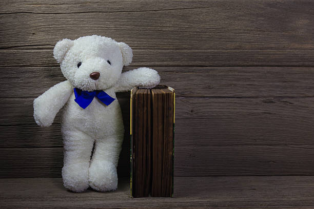 istock Teddy bear with old book on wood background, still life 498140294