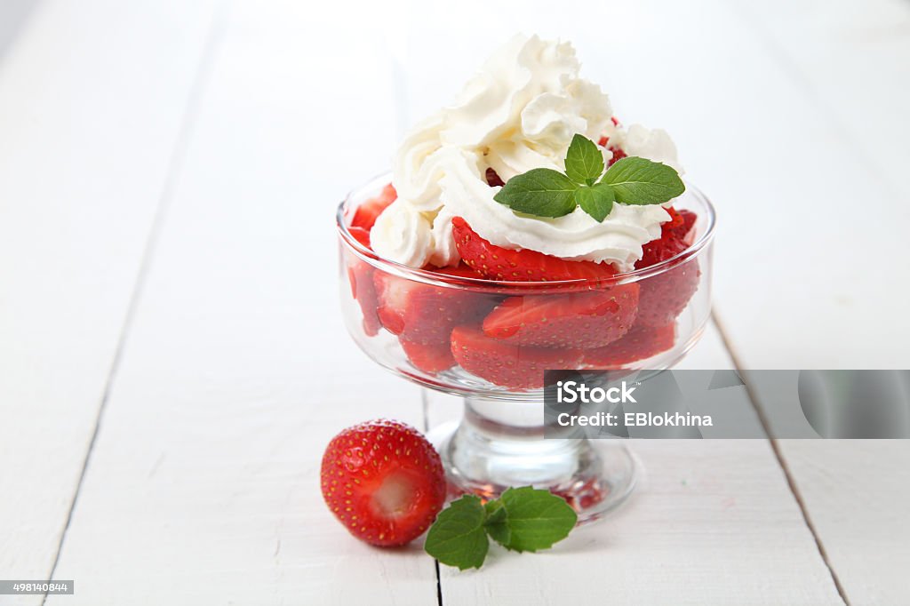 Strawberries and cream Summer dessert: strawberries and cream on a wooden table 2015 Stock Photo