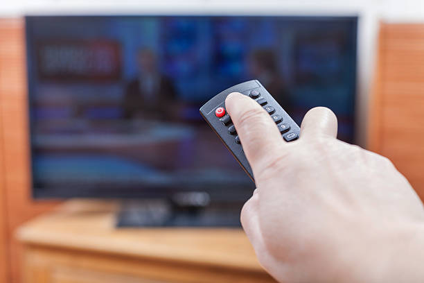 istock Hand turns on News on TV by remote control 498142880