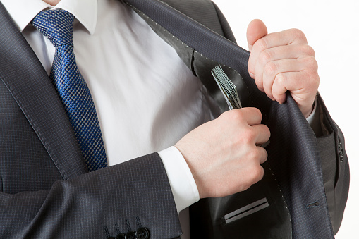 Businessman holding dollars/putting dollars in a pocket, closeup shot