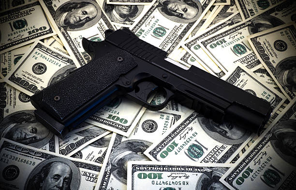 negro y cromo pistola de pistola y dinero dólares de fondo - gun currency crime mafia fotografías e imágenes de stock