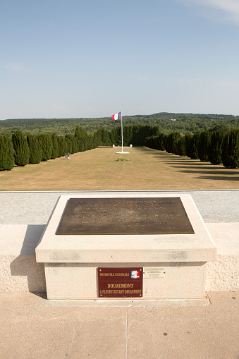 Douaumont, France - July 17, 2015: A large plaque marks the site of the Douaumont Ossuary, where one of the worst battles in history took place during World War I.  Hundreds of thousands of soldiers were killed here.  The French flag flies year round on display.