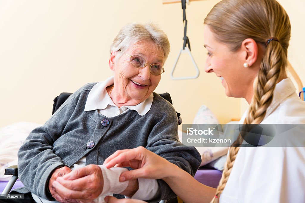 Nurse taking care of senior woman in retirement home Nurse taking care of senior woman in retirement home bandaging a wound Wound Stock Photo