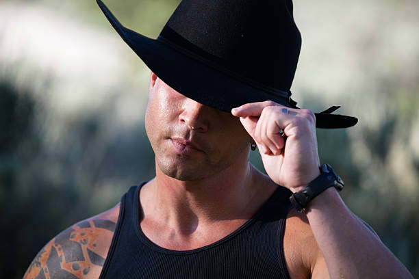 macho montana cowboy dicas seu chapéu preto stetson - dimple imagens e fotografias de stock