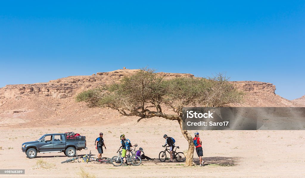 Have a brake in the desert, Jordan A group of mountainbikers is taking a brake in the shadow of a tree on their desert expedition nearby Wadi Rum, Jordan. Desert Area Stock Photo