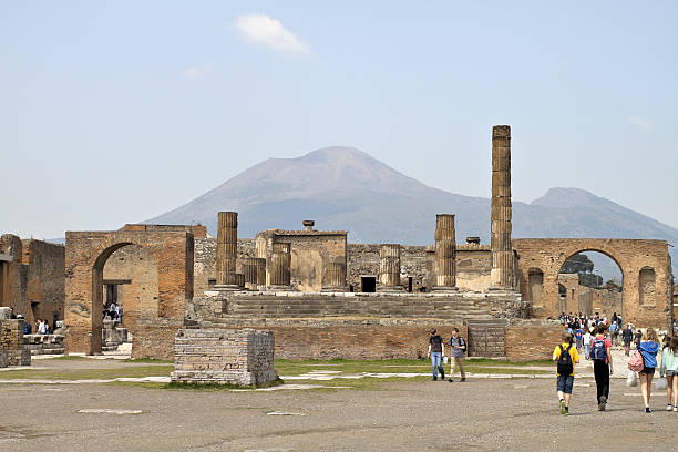 The forum at Pompeii was a grand meeting place for townsfolk, starting its life as a small market place. It developed over the years, that development probably being halted by a severe earthquake in 62 AD. This was followed in 79 AD by the catclysmic volcanic eruption of Mount Vesuvius, which resulted in a rapid pyroclastic flow that buried the town and preserved its ruins for nearly 2000 years. Mount Vesuvius is the larger of the two humps on the horizon. The smaller hump (on the right) is the edge of an even larger old volcano, Mount Somma, within whose crater Mount Vesuvius lies.
