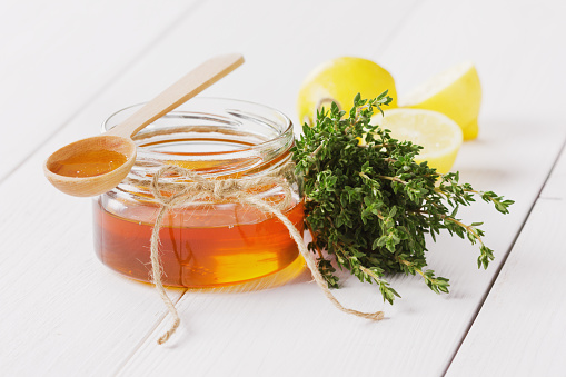 Honey in a wooden spoon and jar on a white background