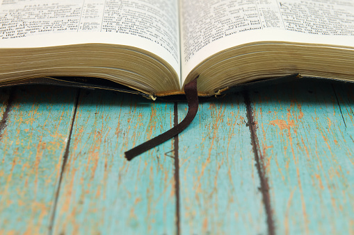 An open Bible with a bookmark on a wooden background