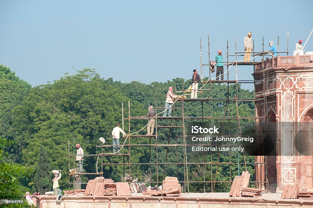 Construction in India New Delhi, India - November 21, 2010: Manual workers raise building materials by hand up scaffold while working on a project to restore Humayun's Tomb. Adult Stock Photo