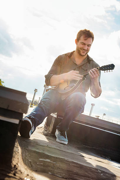 istock Young man playing his mandolin on Brooklyn rooftop 498174586