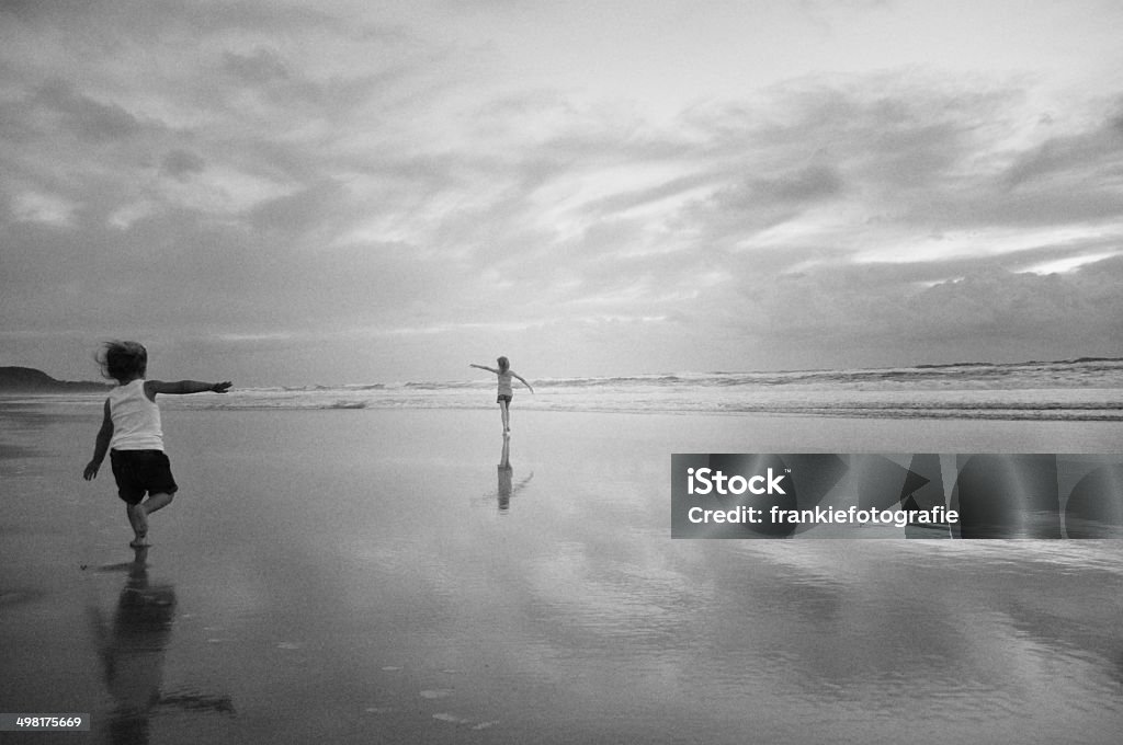 Two girls running along beach Two girls playing at the beach. Black And White Stock Photo