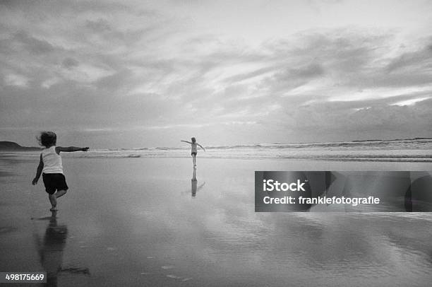 Two Girls Running Along Beach Stock Photo - Download Image Now - Black And White, Blue, Cheerful