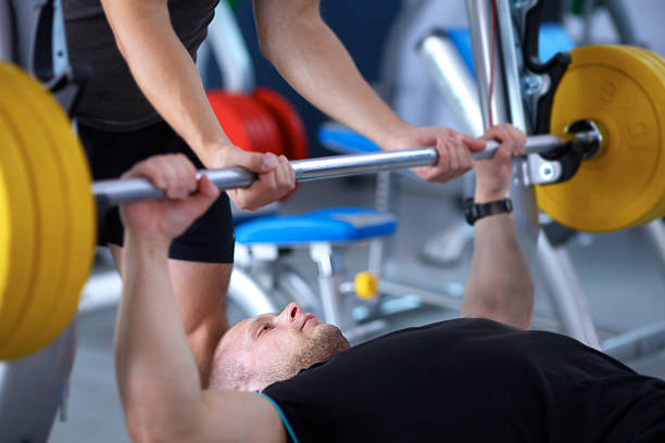 istock Young man lifting the barbell in gym with instructor 498186666