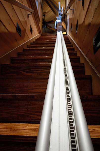 Chair lift on wooden stairway Photograph looking up rack rail on chair lift on wooden stairs. Image taken from bottom of stairs looking up the rack rail to the chair folded up at the top of the stairs. rack and pinion pictures stock pictures, royalty-free photos & images
