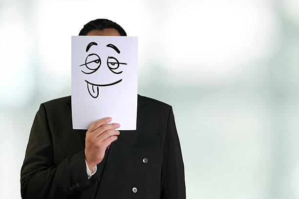 Business concept image of a businessman holding white paper mask with silly face drawn on it